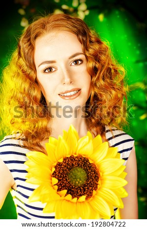 Beautiful red-haired girl with sunflower smiling at camera. Summer.