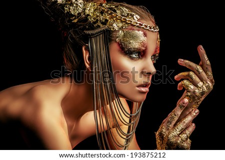 Art project: beautiful woman with golden make-up. Jewelry, make-up. Fashion. Over black background.