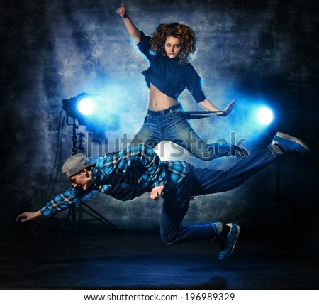 Two modern dancers jumping over grunge background. Hip-hop. Urban, disco style.