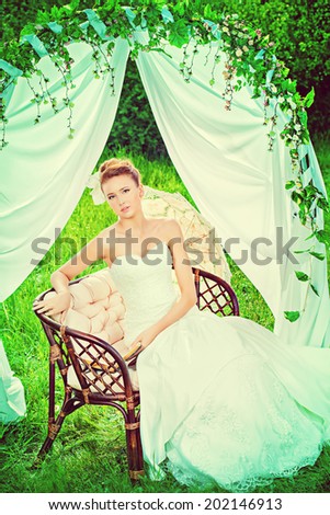 Charming elegant bride under the wedding arch. Wedding dress and accessories. Wedding decoration.