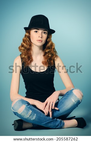 Elegant red-haired girl sitting on a floor. Full length portrait.