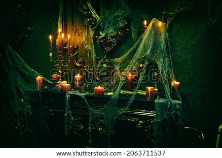Halloween scary stories. Portrait of a dark scary room in the old vintage castle with Halloween decorations, burning candles and cobweb around. 
