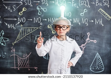 New ideas and discoveries. A smart scientist girl stands at the blackboard with chemical formulas in a hat with a luminous light bulb on her head and raises her index finger. Eureka! Education.  Сток-фото © 