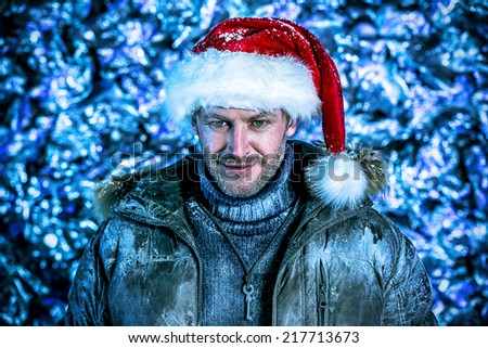 Handsome smiling man dressed in winter clothes and Santa Claus cap covered with frost. Christmas.