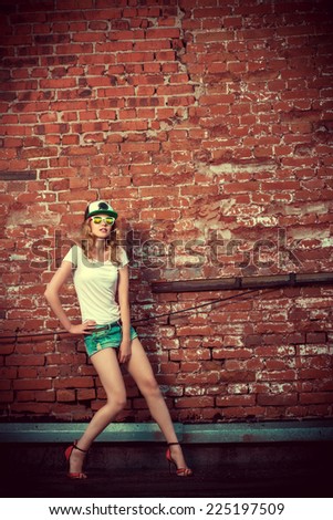 Beautiful modern girl near the brickwall. Youth style. Fashion shot.