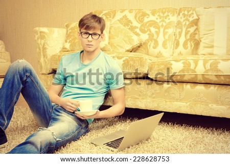 Casual young man sitting on the floor with a laptop in the comfort of his home.