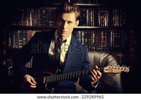 Handsome young man playing rock-n-roll music on his electric guitar. Retro, vintage style.