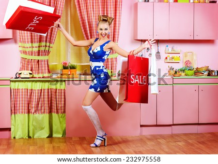Fashionable pin-up girl standing with shopping bags on a pink kitchen. Retro style. Sale.