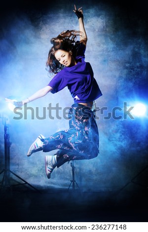 Beautiful hip-hop dancer jumping over grunge background.