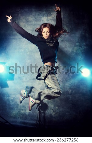 Beautiful hip-hop dancer jumping over grunge background.