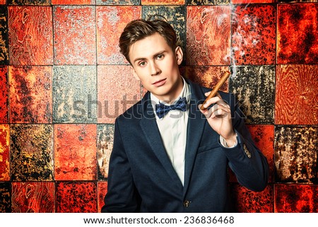 Handsome young man in elegant suit smoking a cigar.