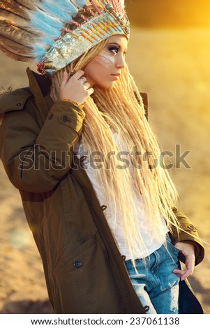 Portrait of a beautiful girl in style of the American Indians on a sunset. Western style. Jeans fashion.