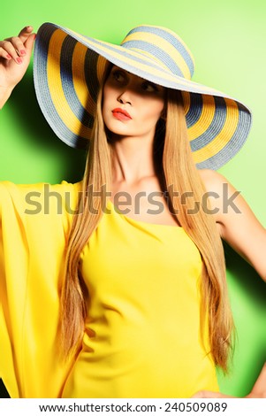 Portrait of a stunning fashionable lady in bright yellow dress posing over  green background. Beauty, fashion concept. Colors of summer.