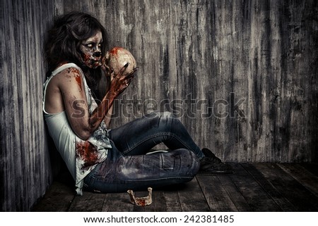 Frightening bloody zombie girl with a skull. Halloween.