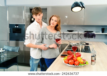 Happy young couple in love cooking a dinner on a kitchen and drink red wine. Healthy food. Happy family.