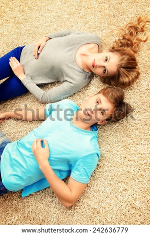 Unhappy young people lying on a carpet and looking to camera. Relationships.