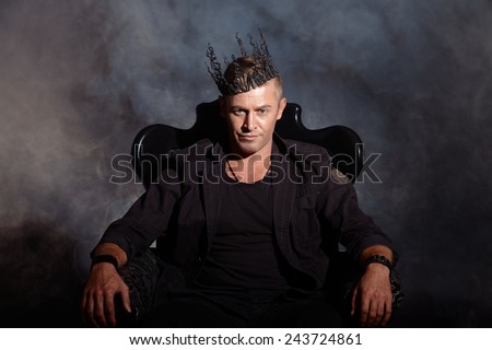 Portrait of a masculine handsome man in elegant black suit sitting in a chair in a classic vintage style.