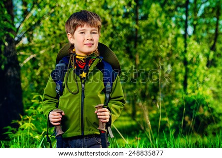 Portrait of a cute 7 years old boy in tourist clothes posing outdoor. Summer day.