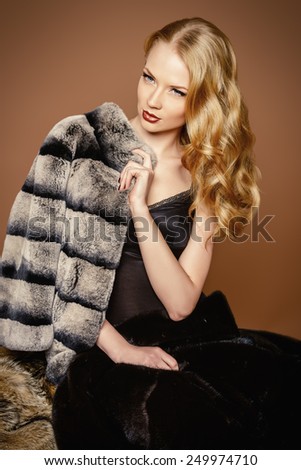 Elegant woman with beautiful blonde hair posing in furs. Luxury, rich lifestyle. Fashion photo.