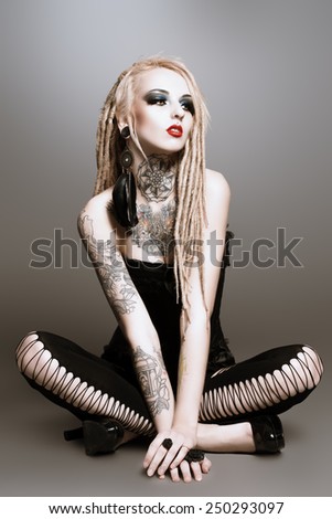 Full length portrait of a gorgeous sexy girl with black make-up and long dreadlocks. Gothic style. Fashion. Cosmetics, hairstyle. Tattoo.