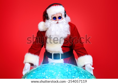 Santa Claus DJ near brilliant sparkling disco ball. Christmas celebration.