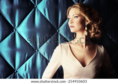 Portrait of a beautiful woman in elegant evening dress posing over vintage background. Jewellery.  Fashion shot. Hairstyle.