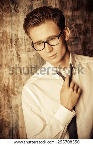 Portrait of a handsome young man in elegant suit standing over grunge background.