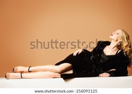 Beautiful blonde woman wearing mink fur coat. Fashion, beauty. Luxurious lifestyle. Studio shot.