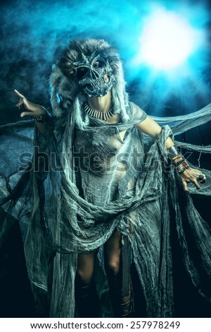 Frightening female wearing mask of skull. Fantasy. Halloween. Witchcraft, voodoo dances.