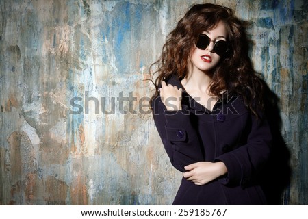Close-up portrait of a sexual woman with beautiful curly hair alluring by the grunge wall. Fashion, beauty and love concept.