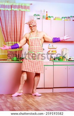 Happy muscular man in an apron standing in the pink kitchen. Love concept. Valentine\'s day. Women\'s day.
