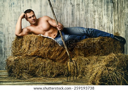 Sexy muscular cowboy lying on a haystack. Western style.