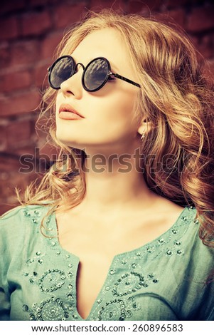 Lovely young woman in casual blouse and sunglasses outdoor. Fashion shot.