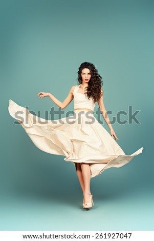 Fashion shot of the elegant woman in beautiful long dress posing in motion. Studio shot.