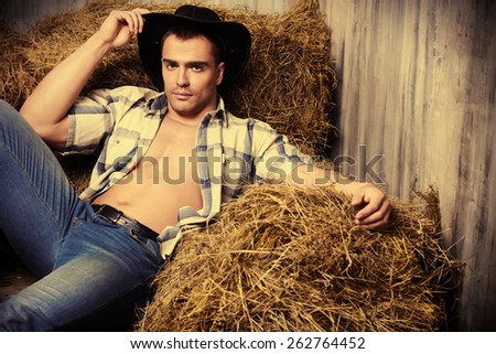 Sexy cowboy lying on a haystack. Western style. Jeans denim fashion.