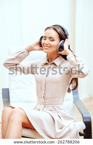 Happy young woman resting at home listening to music in headphones.