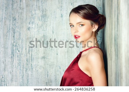 Sensual young lady in red dress posing an studio. Beauty, fashion concept.
