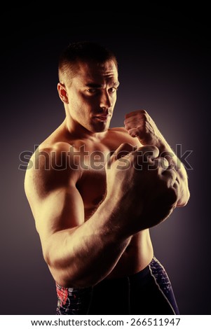 Strong muscular man fighting with fists. Martial arts. Fist fights, boxing. Bodybuilding. Black background.