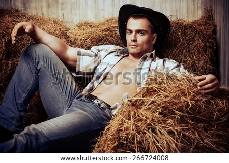 Sexy cowboy lying on a haystack. Western style. Jeans denim fashion.