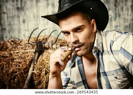 Sexy cowboy smoking a cigar. Western style. Jeans denim fashion.