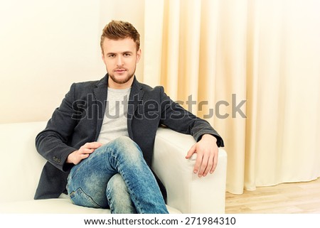 Handsome young man sitting relaxed on a sofa.