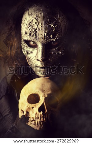 Mysterious man in iron mask holding skull. Steampunk. Fantasy. Halloween.