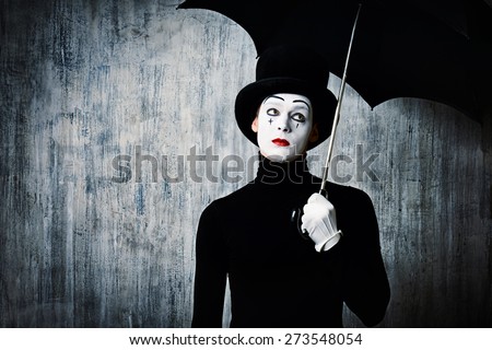 Portrait of a male mime artist standing under umbrella expressing sadness and loneliness. Grunge background.