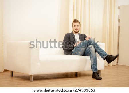 Handsome young man sitting relaxed on a sofa.
