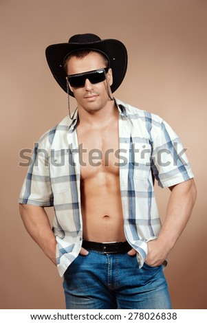 Portrait of a sexy cowboy man posing at studio. Western style. Denim, jeans.