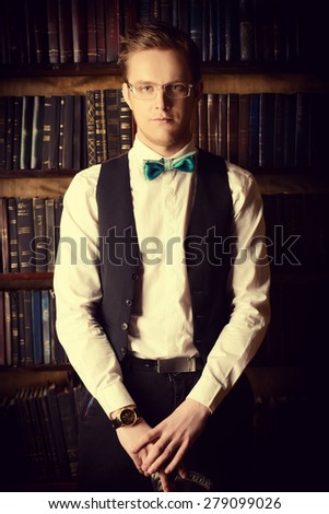Young handsome man in evening suit stands in a room with classic vintage interior. Fashion.