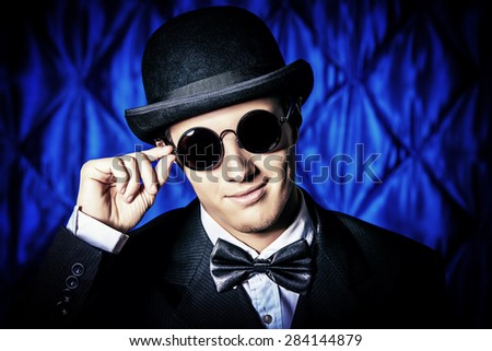 Portrait of an elegant old-fashioned artist man wearing black suit and bowler-hat. Fashion, style. Cinema, theater.