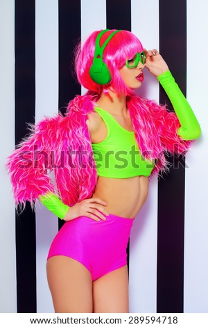 Trendy DJ girl in bright colorful clothes and headphones posing over black-and-white stripes. Party style. Fashion studio shot.