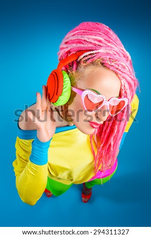 Ultra trendy DJ party girl in bright clothes, headphones and with bright dreadlocks. Disco, party. Show business. Bright fashion.