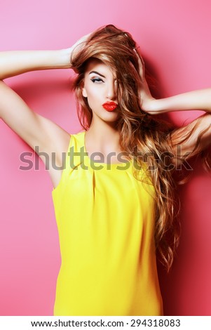 Beautiful fashion model in bright yellow dress posing with her long hair. Beauty, fashion concept. Hair, healthy hair.